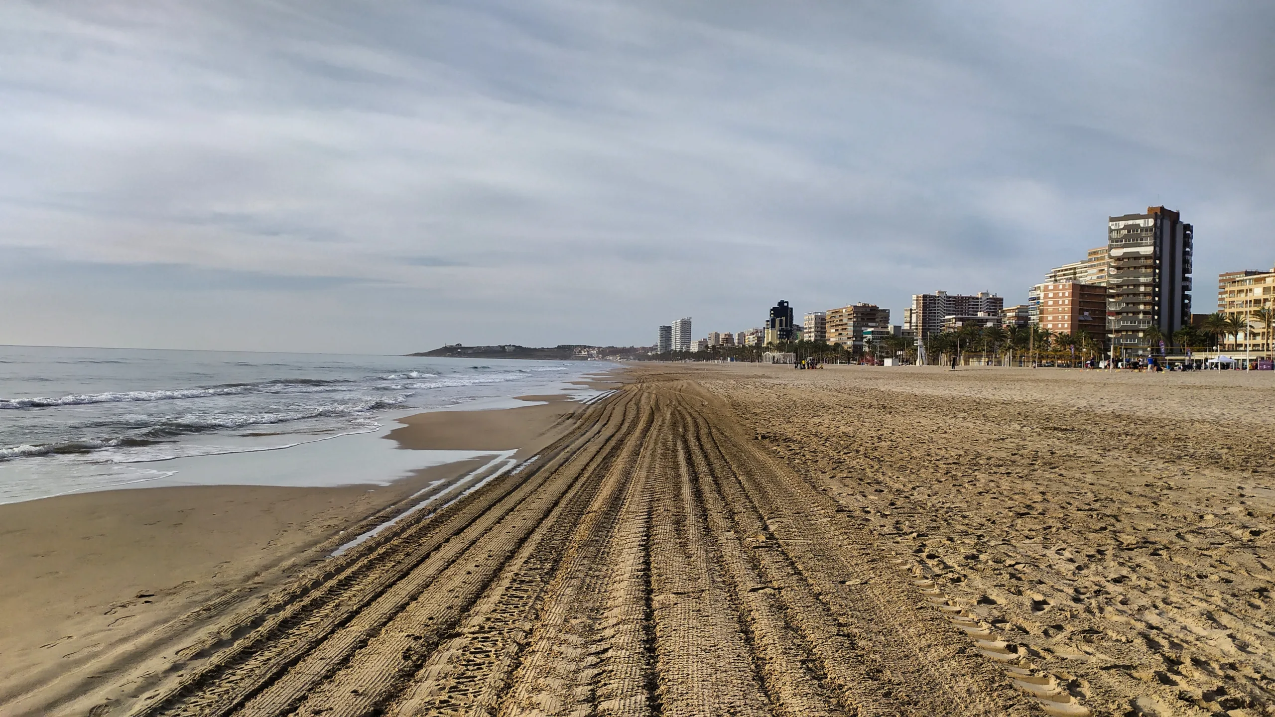 Image of San Juan Beach: the beach appears clean and empty, with golden, soft sand stretching along the coast. The crystal-clear blue sea reflects the sunlight, creating a calm and serene atmosphere. On the horizon, the clear sky blends with the ocean, and there are no people or litter, highlighting the natural beauty of the place.