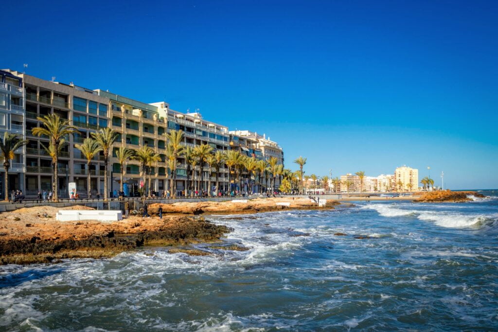 the coast of torrevieja seen from the beach with waves and buildings in the background