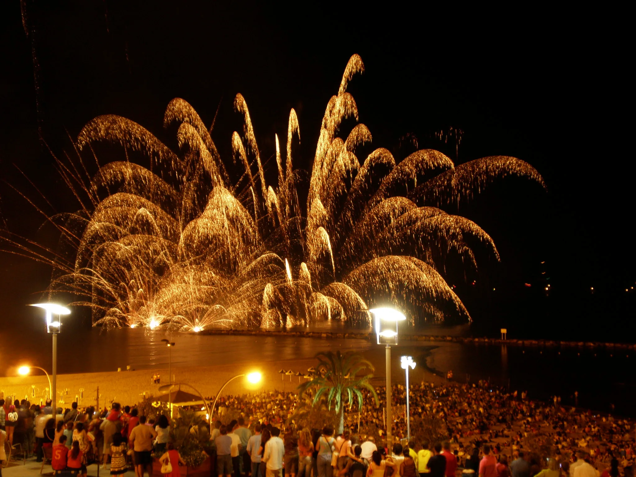 A spectacular fireworks display at Postiguet Beach, lighting up the night sky over the water.