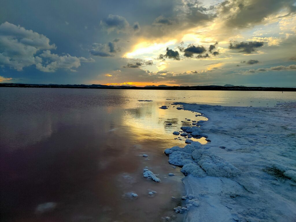 the pink lagoon of torrevieja, alicante, as the sun sets with a salt shore and pink water