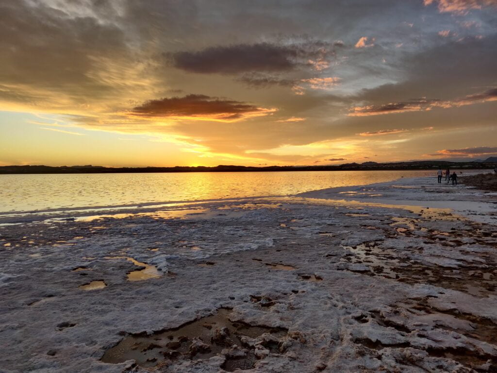 sunset on the pink lagoon of alicante with the shores full of salt and the sun in the background