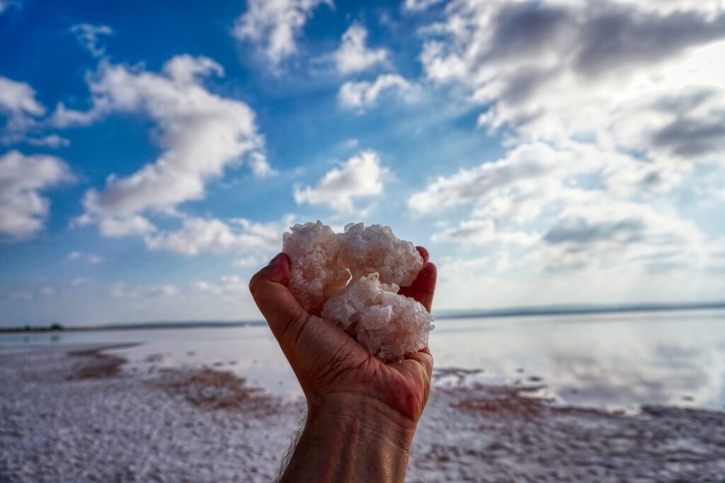 a hand with salt crystals in the pink lagoon of torrevieja with some in the background